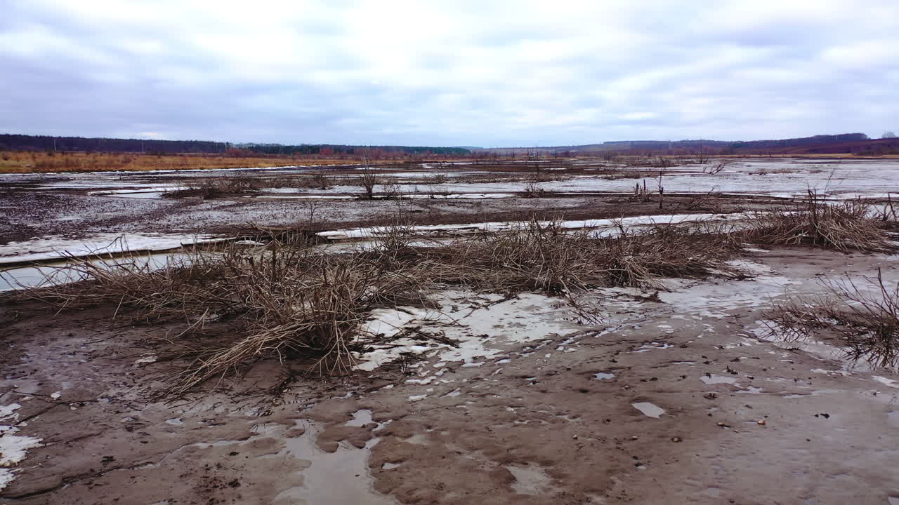 Dead earth destroyed by human development. Global warming. Dried lake with a narrow stream of dirty water. Climate change, ecology. Water problems.