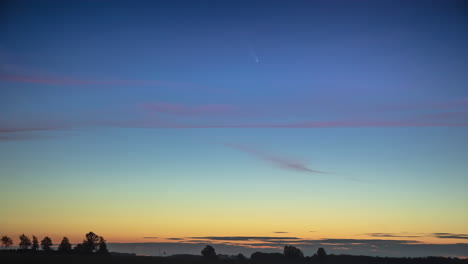 lapso de tiempo del cometa moviéndose poco después de la puesta del sol en lo alto del cielo azul