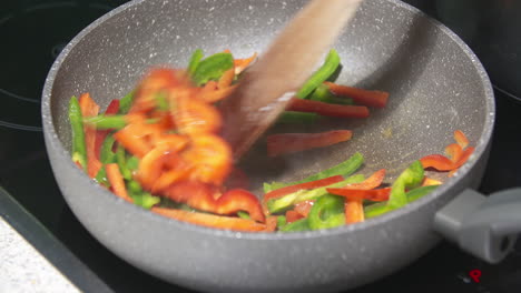 cooking red and green bell peppers in a pan