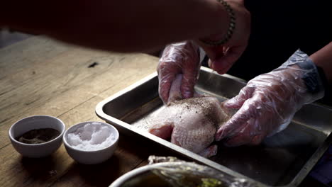 putting salt and pepper on whole raw chicken - traditional balinese cooking class - close up