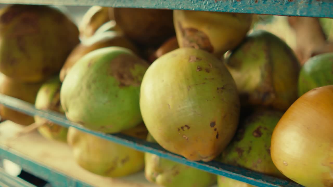 Panoramica a destra di noci di cocco fresche esposte sullo scaffale di un mercato locale, che mostra la texture naturale e i prodotti tropicali nel commercio quotidiano