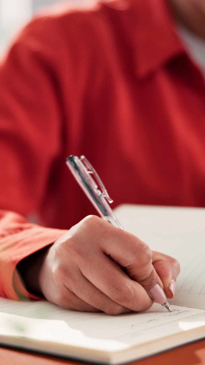 A person writing in a notebook with a pen