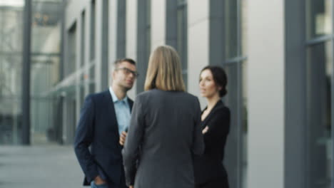 Blurred-Shot-Of-Mature-Businesswoman-Leaving-Business-Partners-And-Coming-Closer-To-Camera-In-The-Street