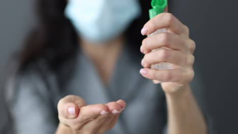 Woman applying hand sanitizer while wearing a medical mask