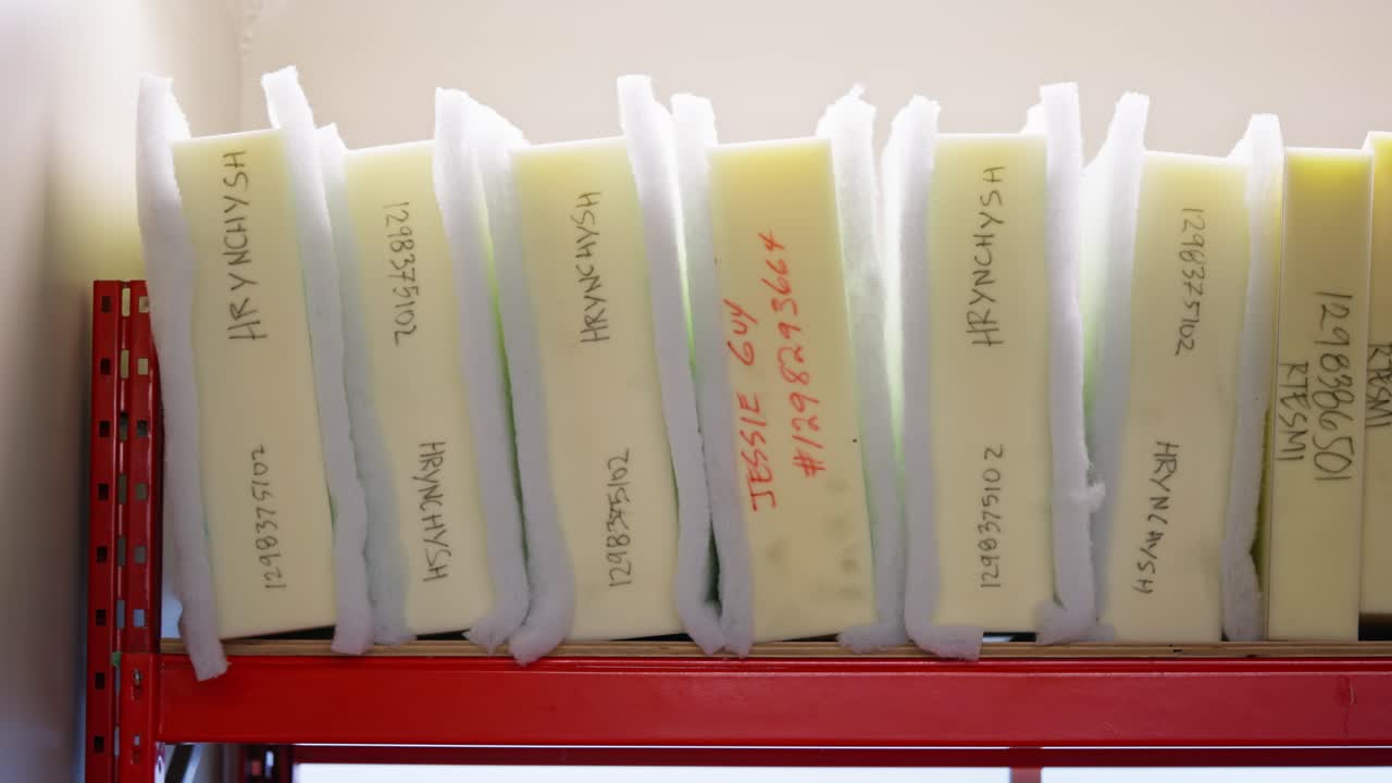 Row of labeled foam cushion blocks sits on industrial shelf in workshop