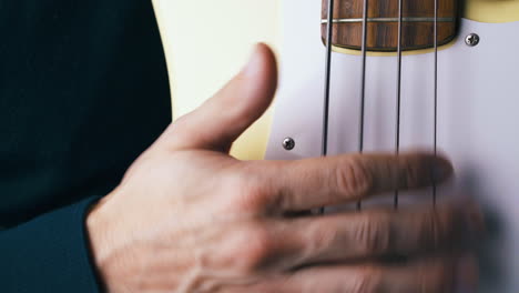 Der-Erfahrene-Bassist-Gibt-Das-Tempo-Vor-Und-Schlägt-Den-Weißen-Gitarren-Pickguard