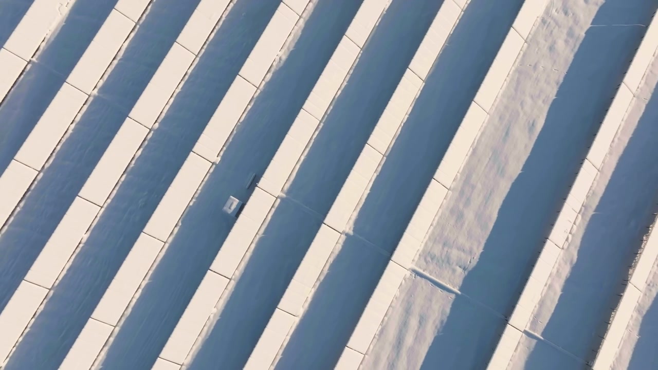 Top-down rotating drone shot of solar energy plant struggling with winter snow
