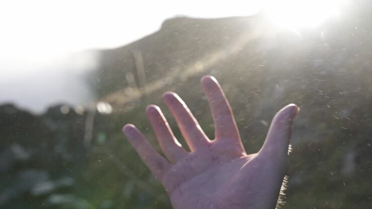 Man touching waterdrops flying near waterfall