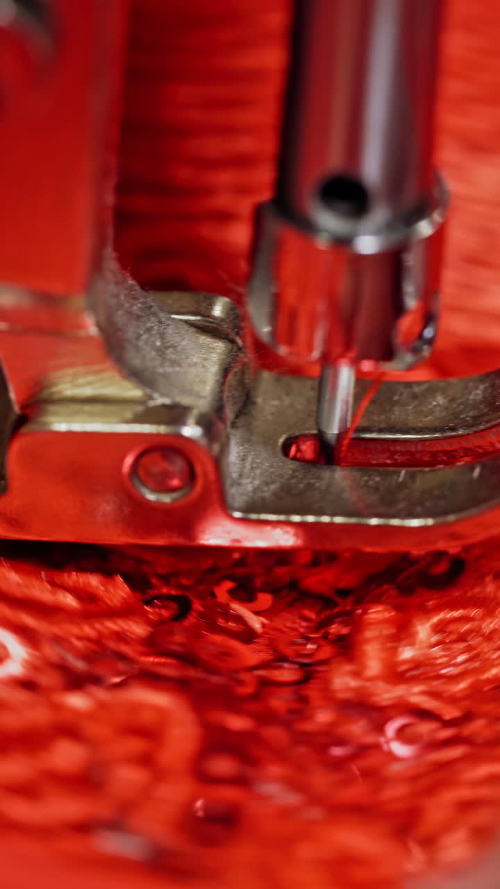 Close-up needle of a sewing machine working on red fabric. Sewing process at making a beautiful flower on a red cloth. Vertical video
