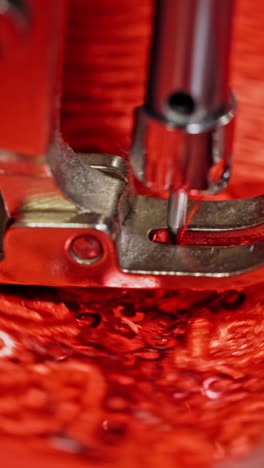 close-up needle of a sewing machine working on red fabric. sewing process at making a beautiful flower on a red cloth. vertical video