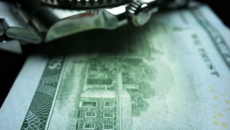 wristwatch lying on one hundred dollar banknote. us cash money