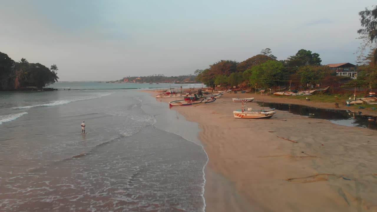 Vista aerea di una spiaggia scenografica con barca e onde all'alba a Weligama, Sri Lanka