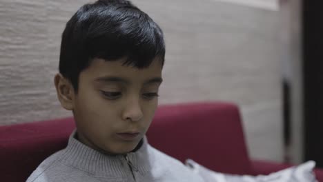 young kid watching mobile and playing online game at home at night from different perspective