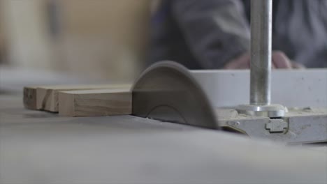 carpintero profesional cortando tablones de madera usando sierra eléctrica en un taller