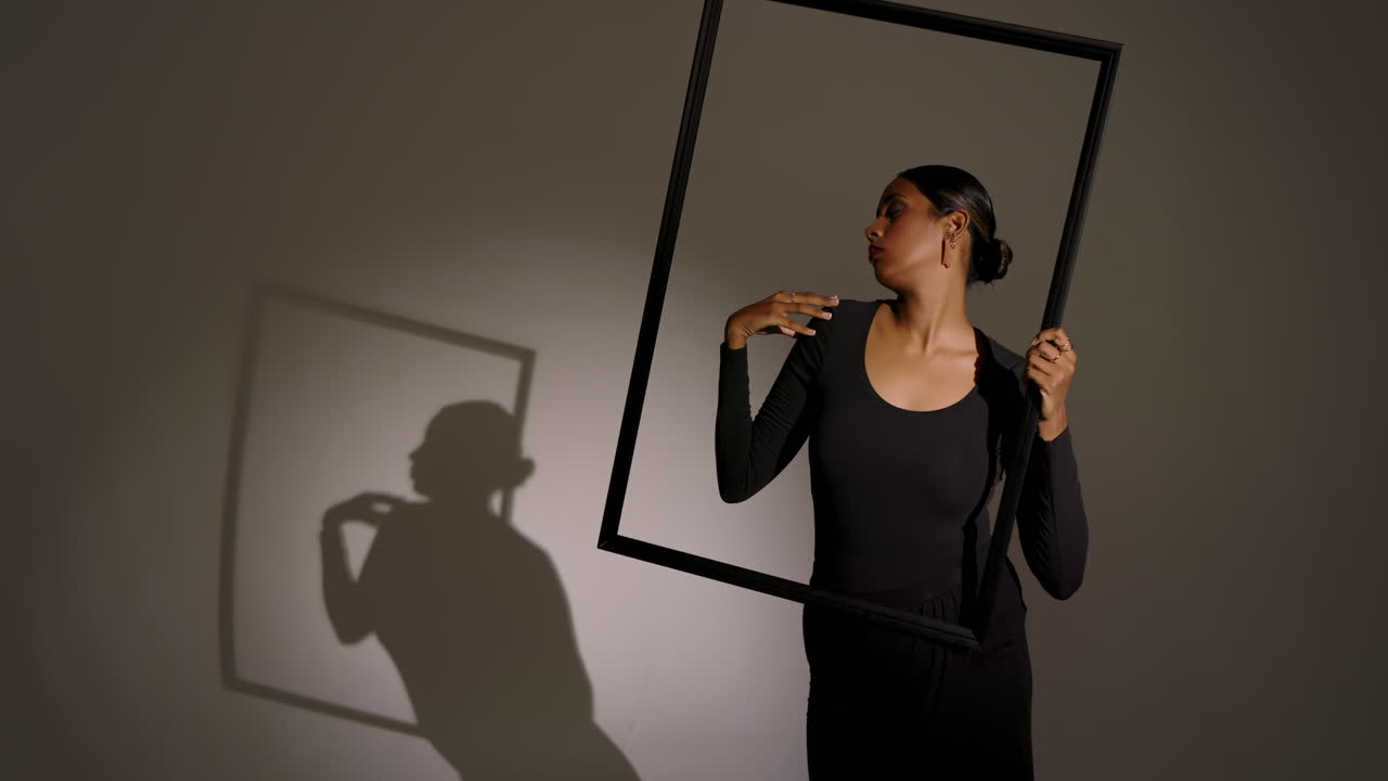 Tilting black frame, Indian woman repositioning it while exploring face alignment at studio