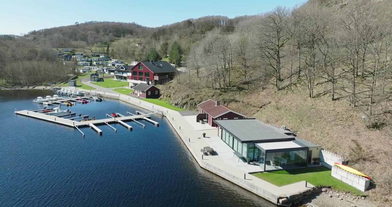Luftaufnahme einer Ferienanlage am Wasser bei Vanse, Norwegen, mit Anlegestellen und Gebäuden.