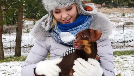 mujer jugando con su pequeño perro fuera del invierno