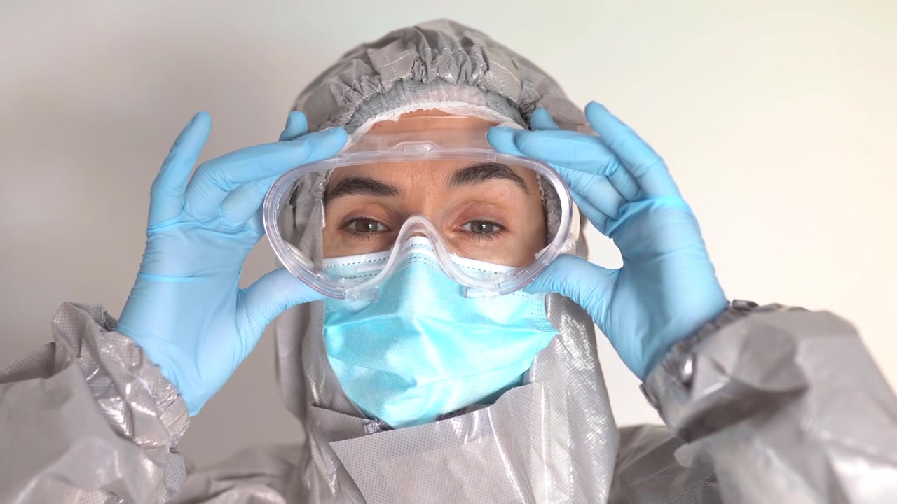 Medico con dispositivi di protezione individuale che indossa gli occhiali di sicurezza.