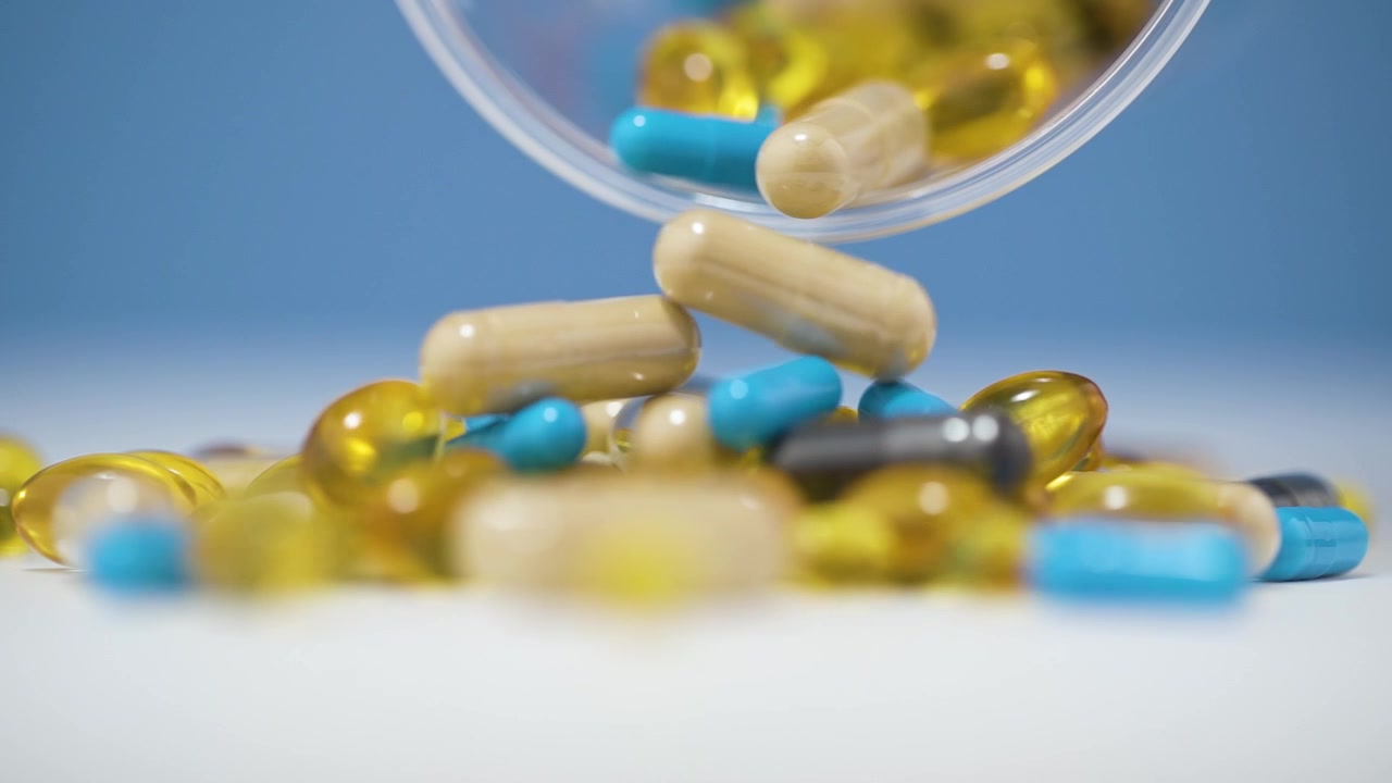 Versando varie pillole capsule mediche colorate da un contenitore con sfondo sfocato, primo piano