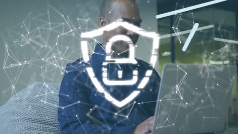 animation of padlock in shield, connected dots over african american businessman working on laptop