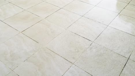 tiled flooring outside with rainwater falling forming a puddle and reflection