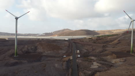 Aerial-shot-going-through-two-wind-turbines-and-making-out-a-greenhouse-in-the-background