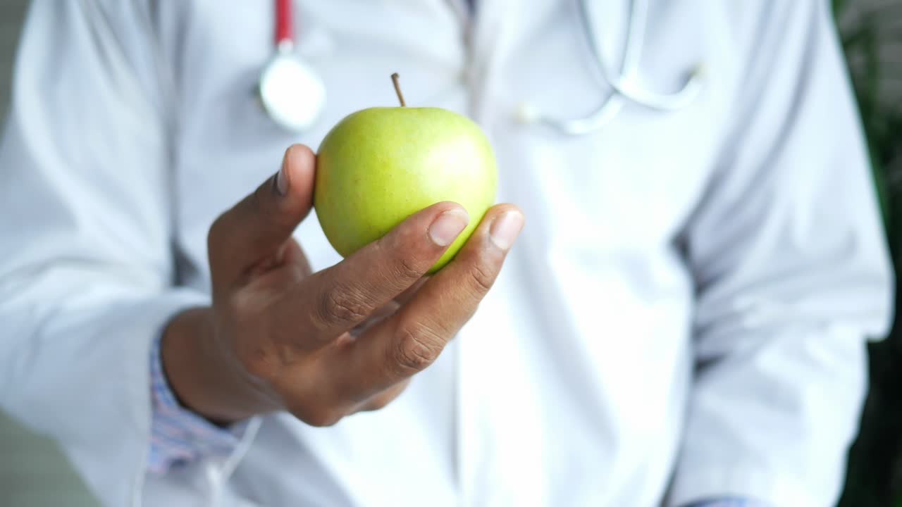 doctor sosteniendo una manzana verde