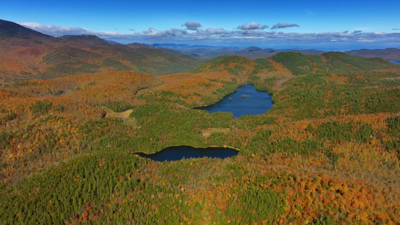 Stunning view of the blue lakes locating among the rocks covered with thick woods. Aerial perspective on colorful forests in mountains. Grey cloudscape in the sky at backdrop.