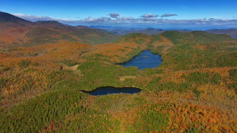 stunning view of the blue lakes locating among the rocks covered with thick woods. aerial perspective on colorful forests in mountains. grey cloudscape in the sky at backdrop.
