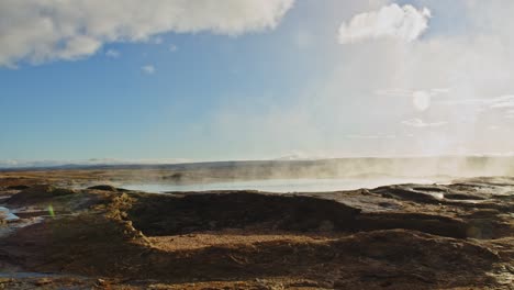 tilt up of geothermal pool with rising steam in haukaladur, iceland on a sunny day