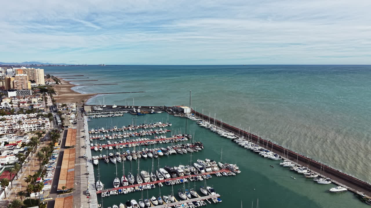 Vista de uma marina com muitos barcos atracados à beira-mar durante o dia, numa zona costeira.