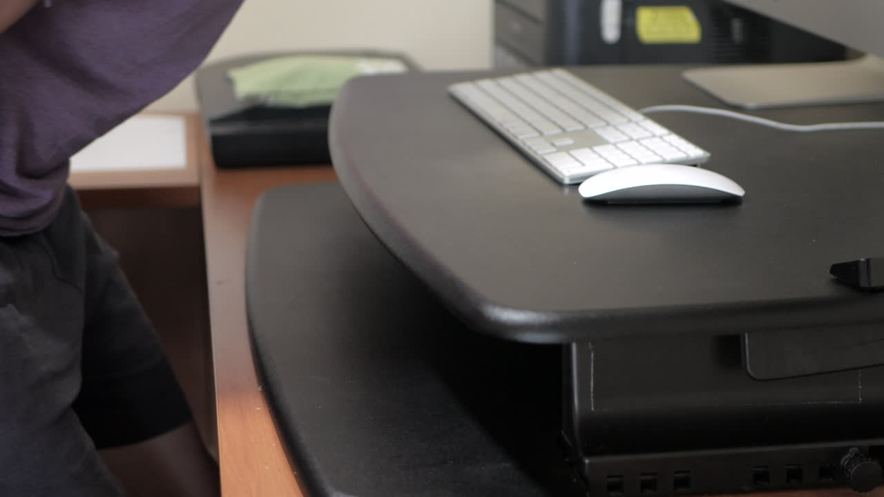 남자는 컴퓨터 워크스테이션의 높이를 조정합니다