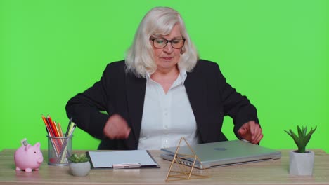 smiling mature business woman sits at workplace office desk, opening laptop computer, start working