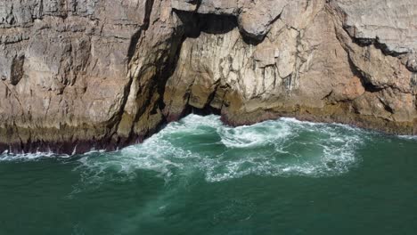 a hole in a cliff spits water