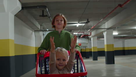 brother pushes his sister in a shopping cart