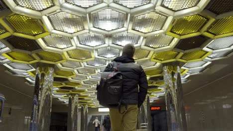 person walking through a metro station with a hexagonal ceiling