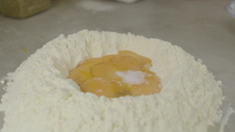 adding salt to flour with egg yolks inside