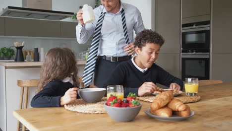 padre empresario en la cocina ayudando a los niños con el desayuno antes de ir a la escuela