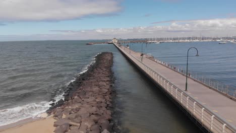 Aerial-forward-flight-over-jetty-and-pier-of-St-Kilda-Beach-in-Melbourne-during-sunny-day