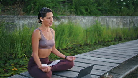 tranquila yogini tableta de meditación en el banco del parque. mujer postura de loto viendo la pestaña
