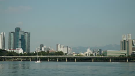 hangang river with day traffic on gangbyeon expressway road and mapo-gu district of seoul bukhansan mountains in background