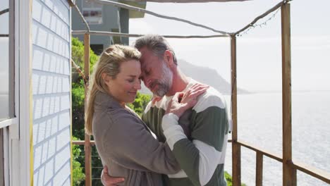 feliz pareja caucásica madura de pie en la terraza junto al mar