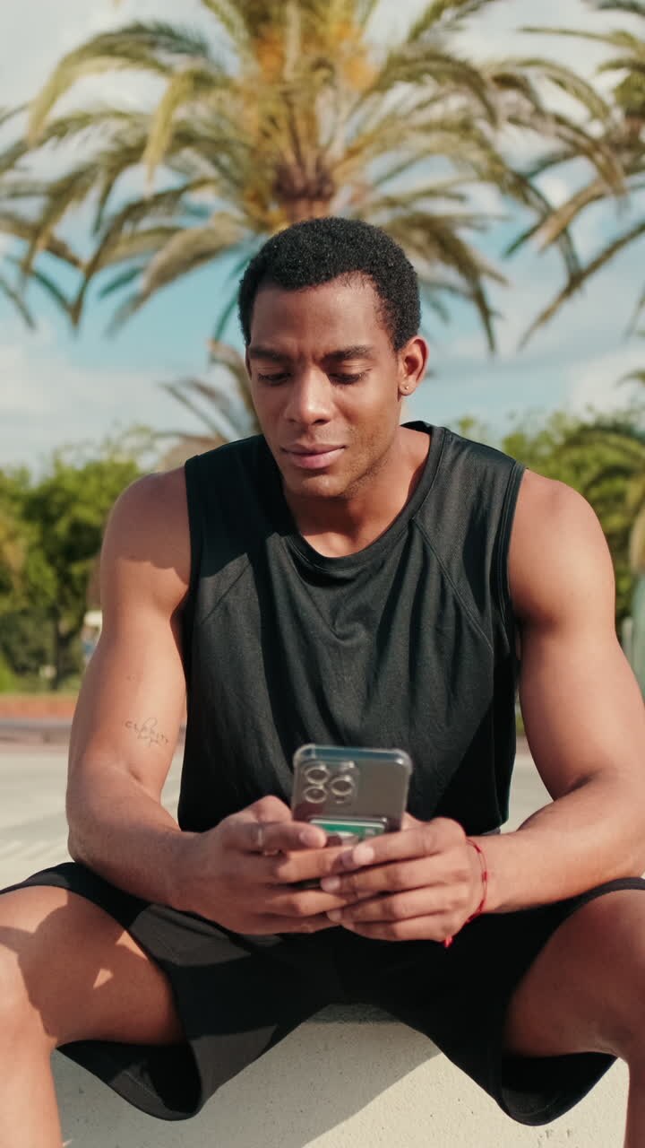 Fit Man Checks Phone in Palm Tree Park