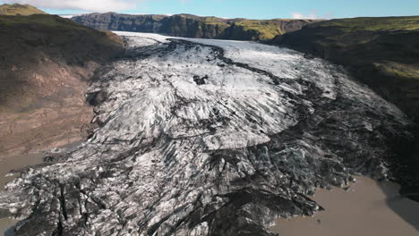 pan up revealing receding glacier in mountain valley of iceland melting into pond