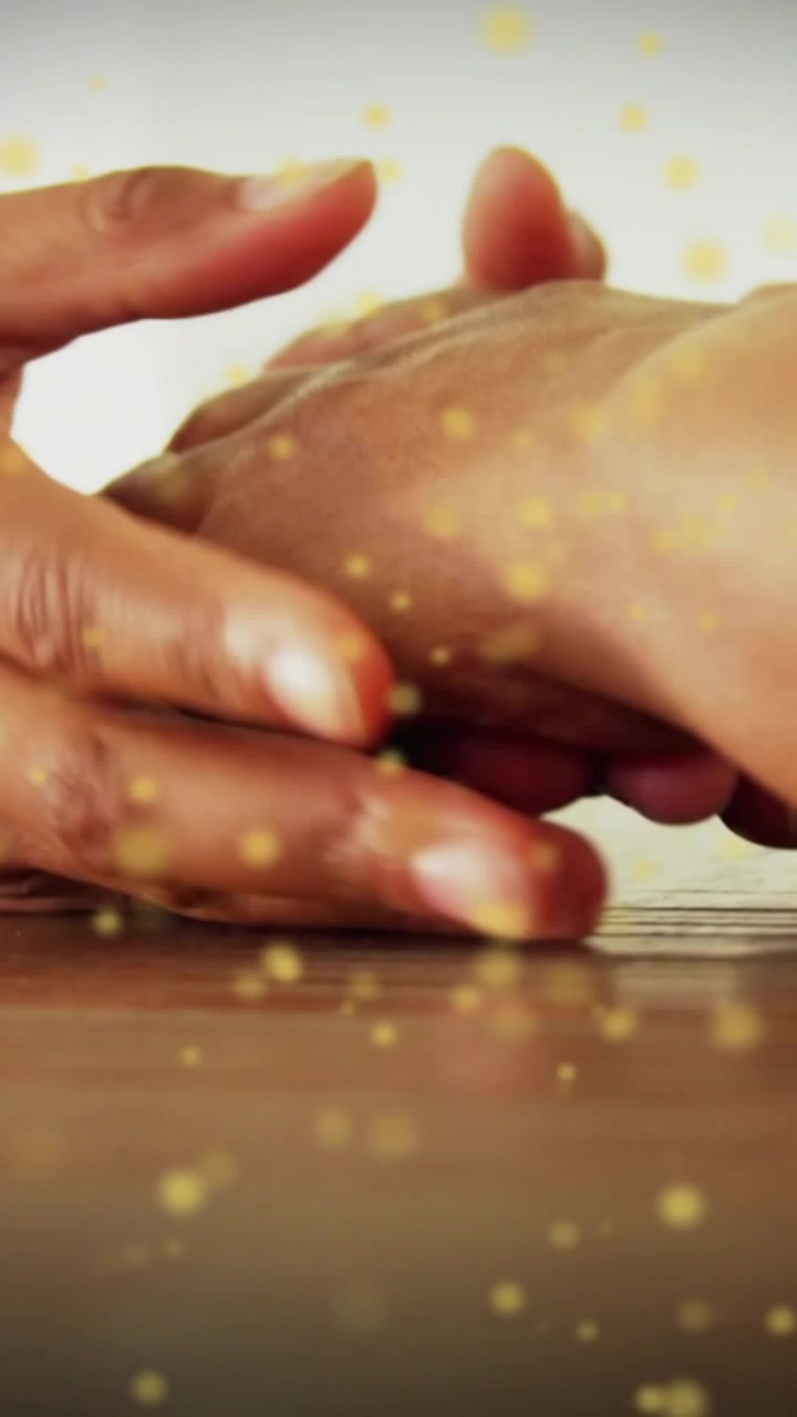 Caregiver initiating shift to cup senior hand on table, golden bokeh drifting over hands for health