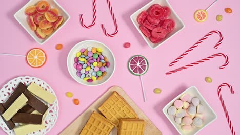 sweet candies and lollypops appear on pastel pink theme. stop motion animation flat lay