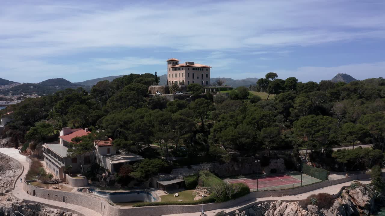 칼라 라자다 마요르카 스탠디그(cala rajada mallorca standig)의 빌라 행진은 푸른 물과 산을 배경으로 있는 언덕 꼭대기에 있습니다.