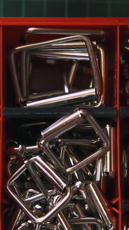 cu: professional woman designer takes fashionable silver accessories from red box section in tailor workshop closeup