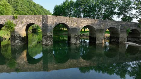 antiguo puente de arco de piedra sobre un río en un entorno rural pacífico