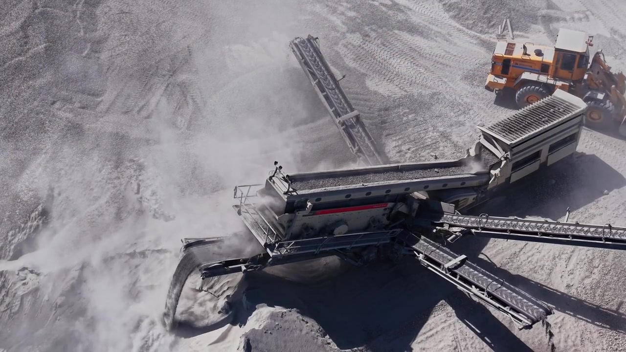 Heavy machinery operates in an industrial site for rock processing